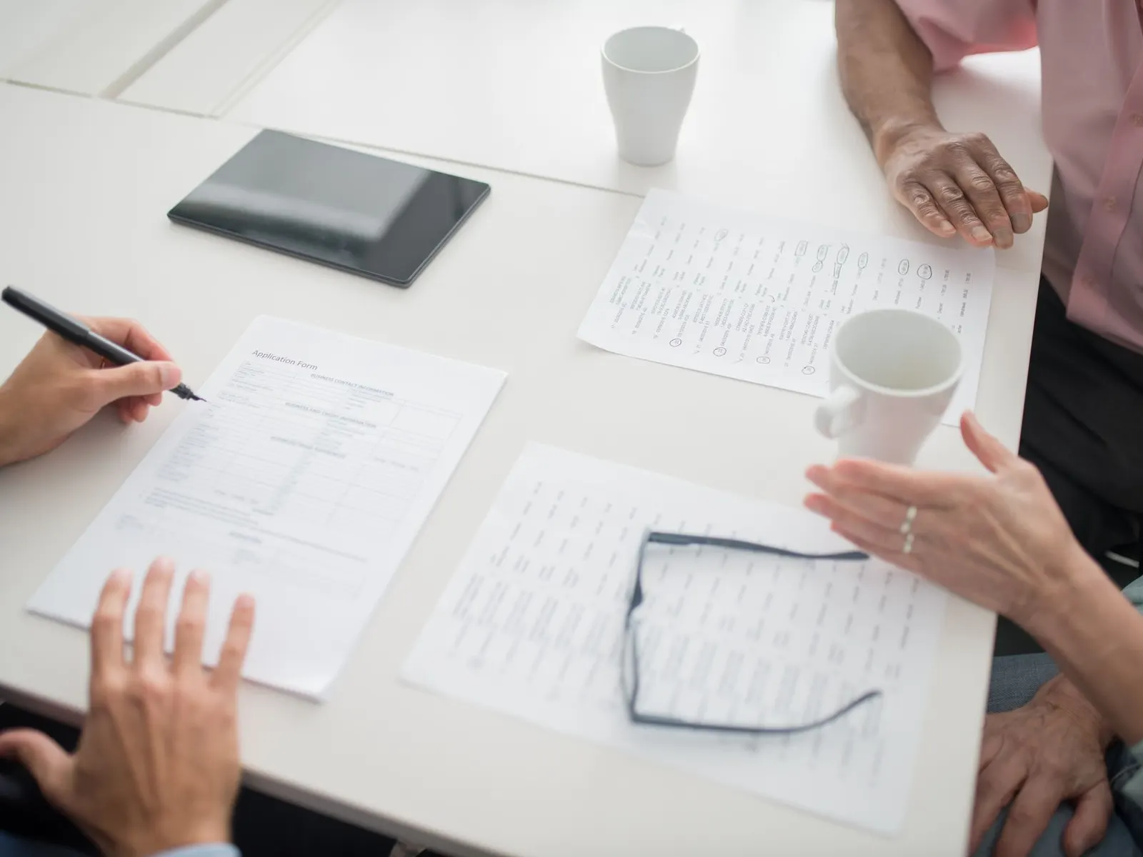 Hands and papers around a table during a work discussion.