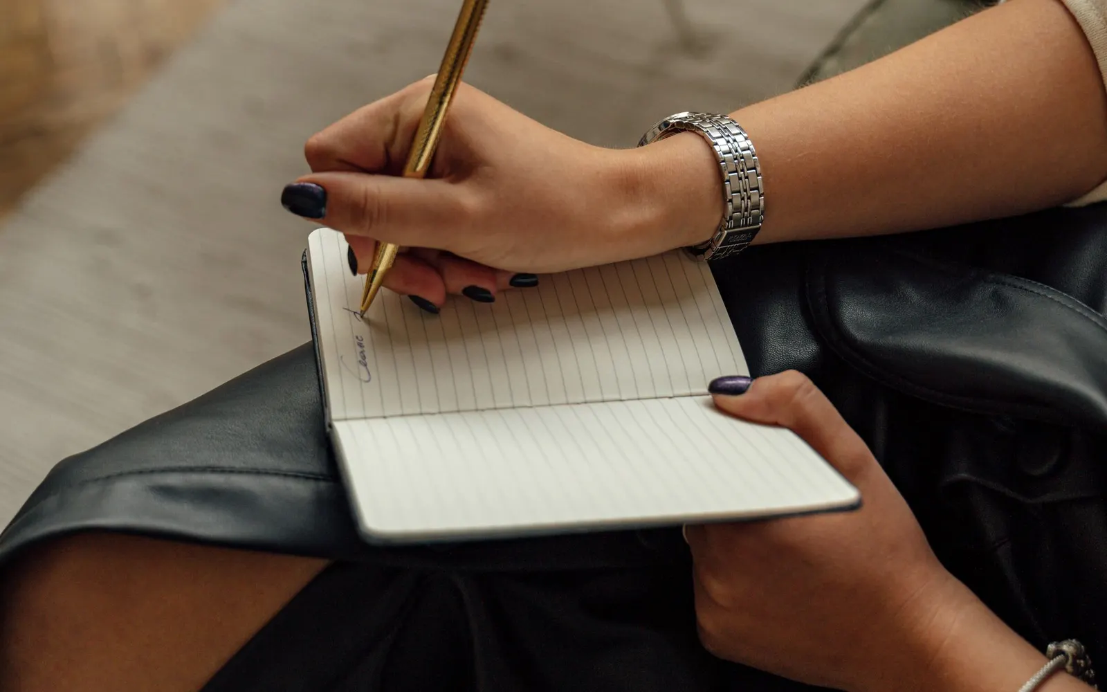 Hands writing notes in a notebook.
